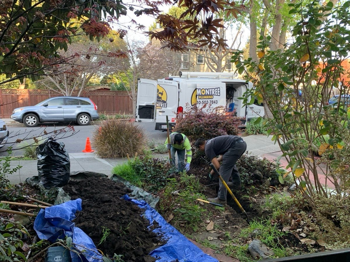 Crew excavating a sewer line trench in a front yard