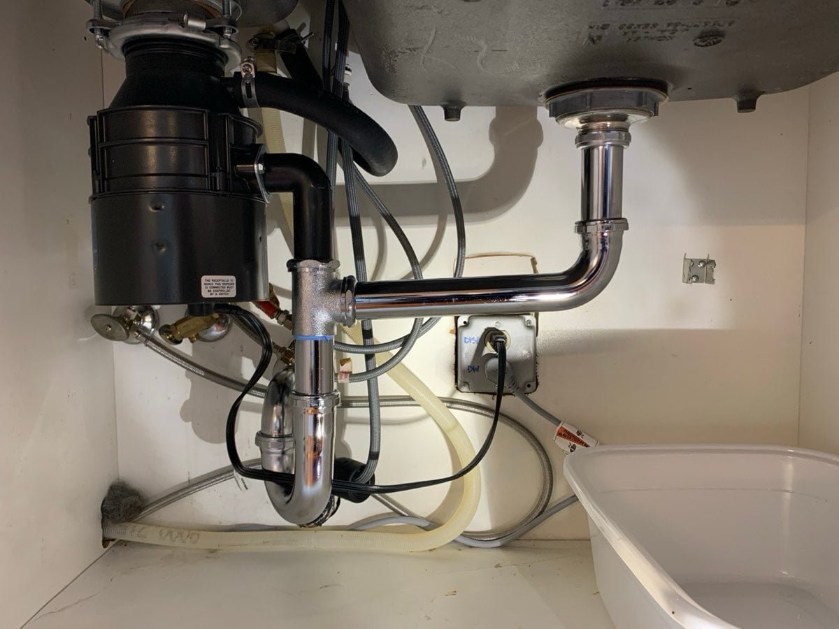 New garbage disposal and chrome drain assembly under a kitchen sink