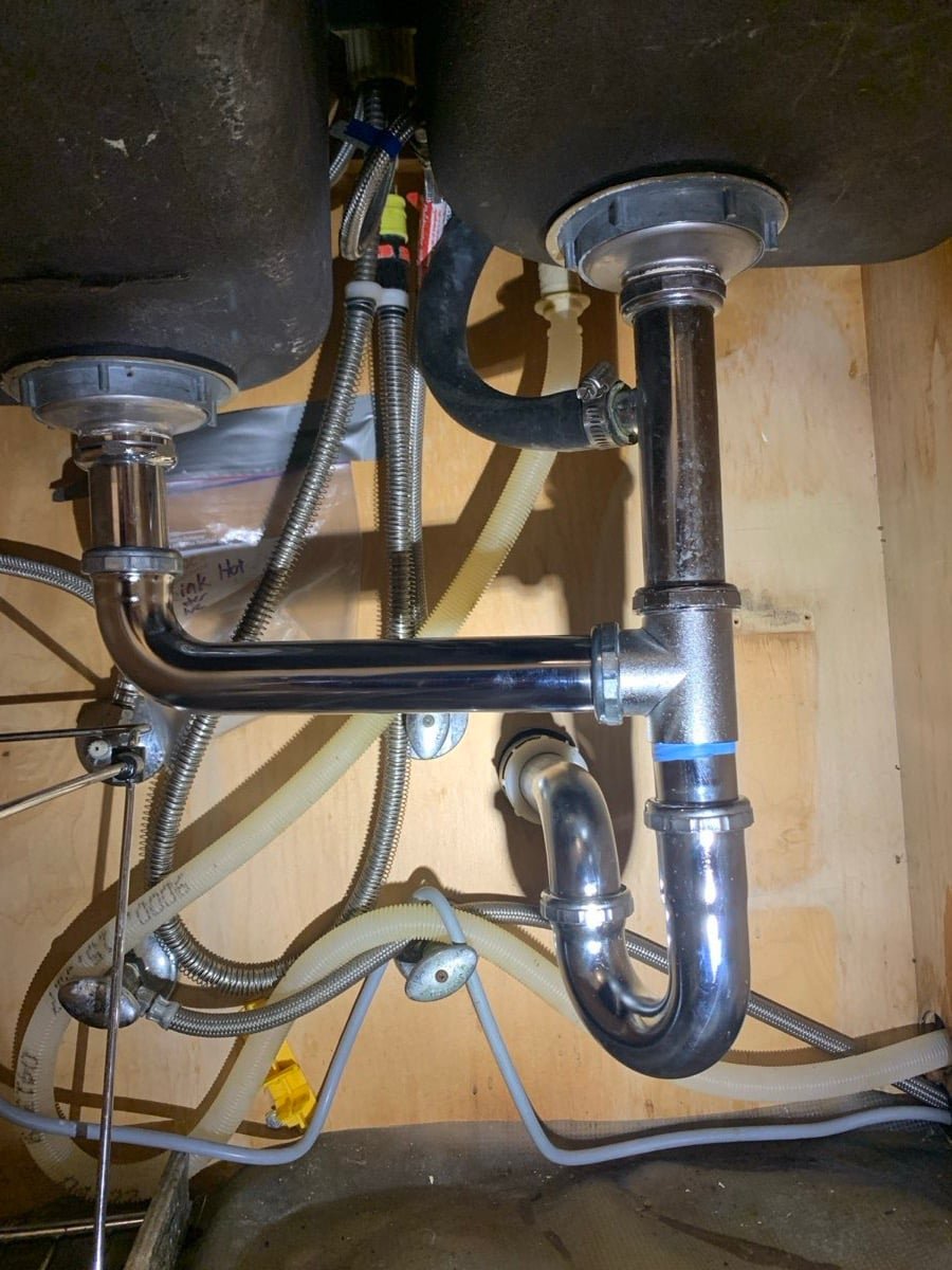 Chrome drain trap assembly under a double-bowl kitchen sink